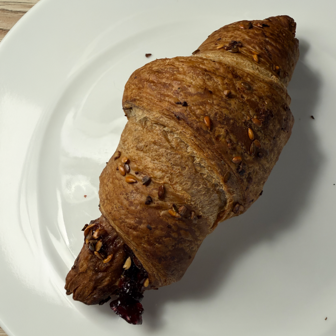 En flaget brun croissant på en hvid tallerken.