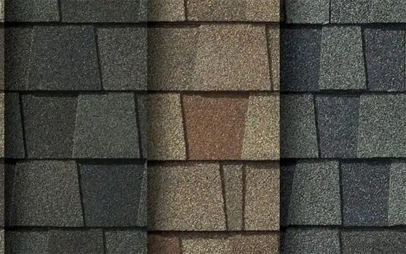 Close-up of overlapping asphalt roof shingles in shades of gray, brown, and tan.
