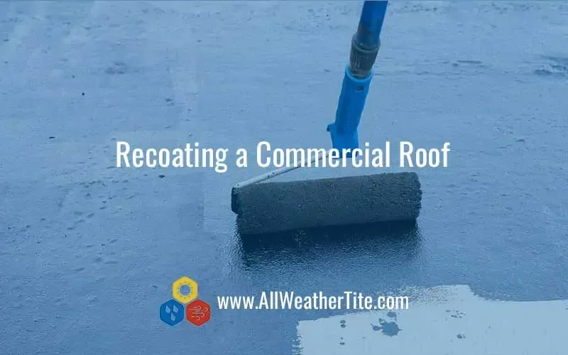 A person recoats a commercial roof with a paint roller. The surface is a blue-grey color, with text