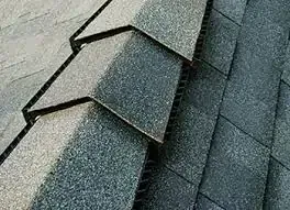 Close-up of dark gray asphalt shingles on a roof, layered in a staggered pattern.