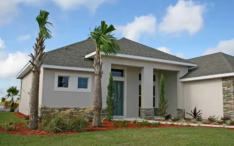 Modern home with light stucco exterior, palm trees, and green lawn.