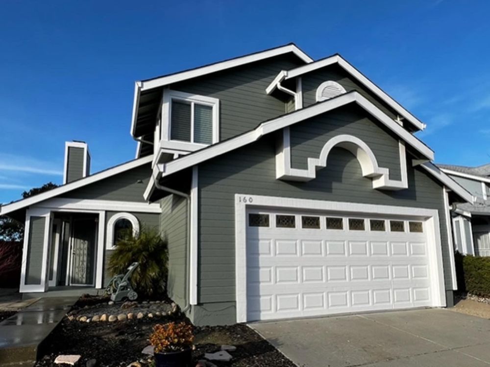 A house with a white garage door and a blue sky in the background