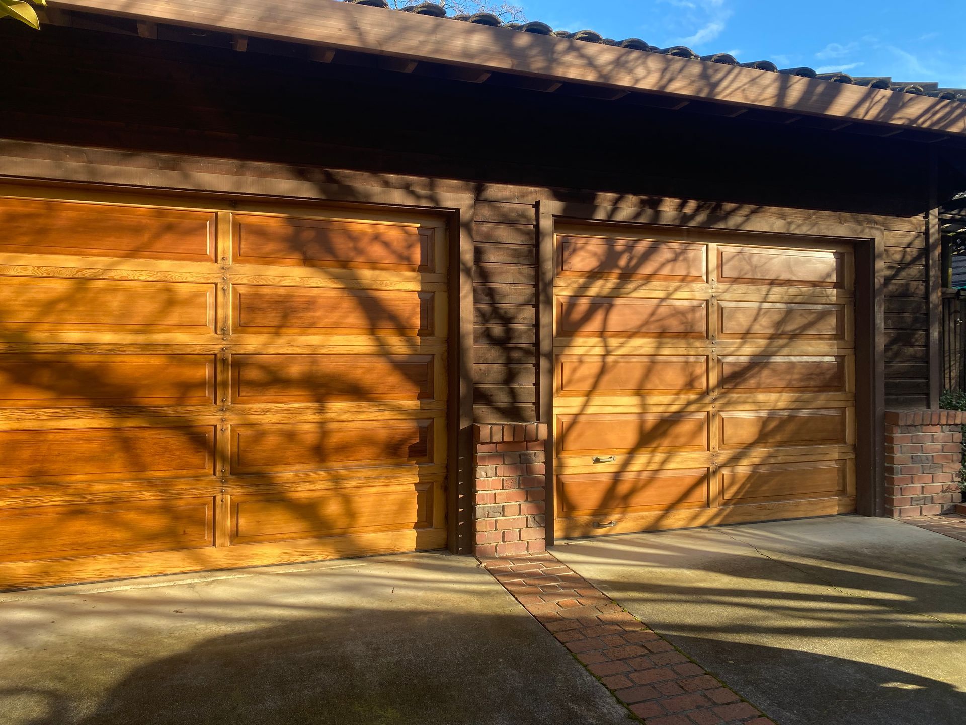 A wooden garage door with a tree shadow on it