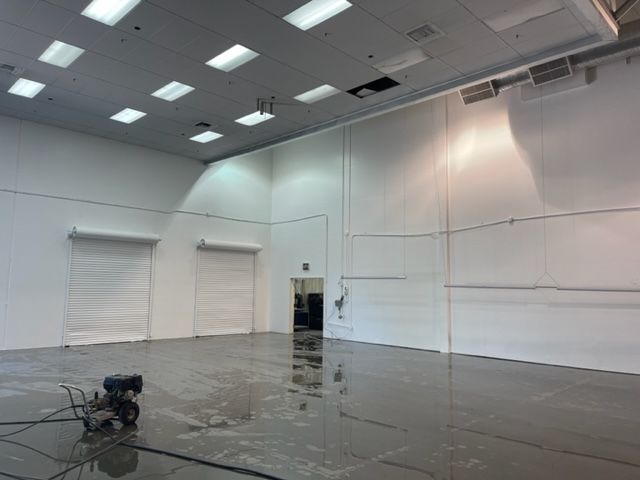 A large empty room with a reflection of a person in the floor.