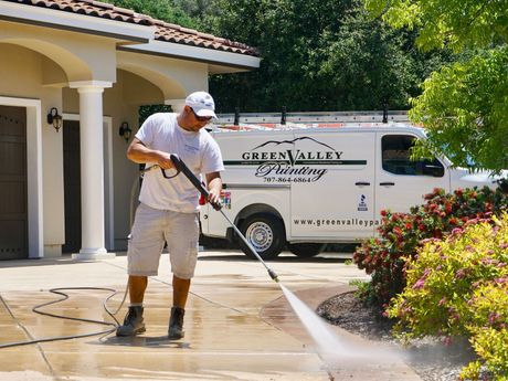 a man is cleaning a driveway in front of a green valley painting van