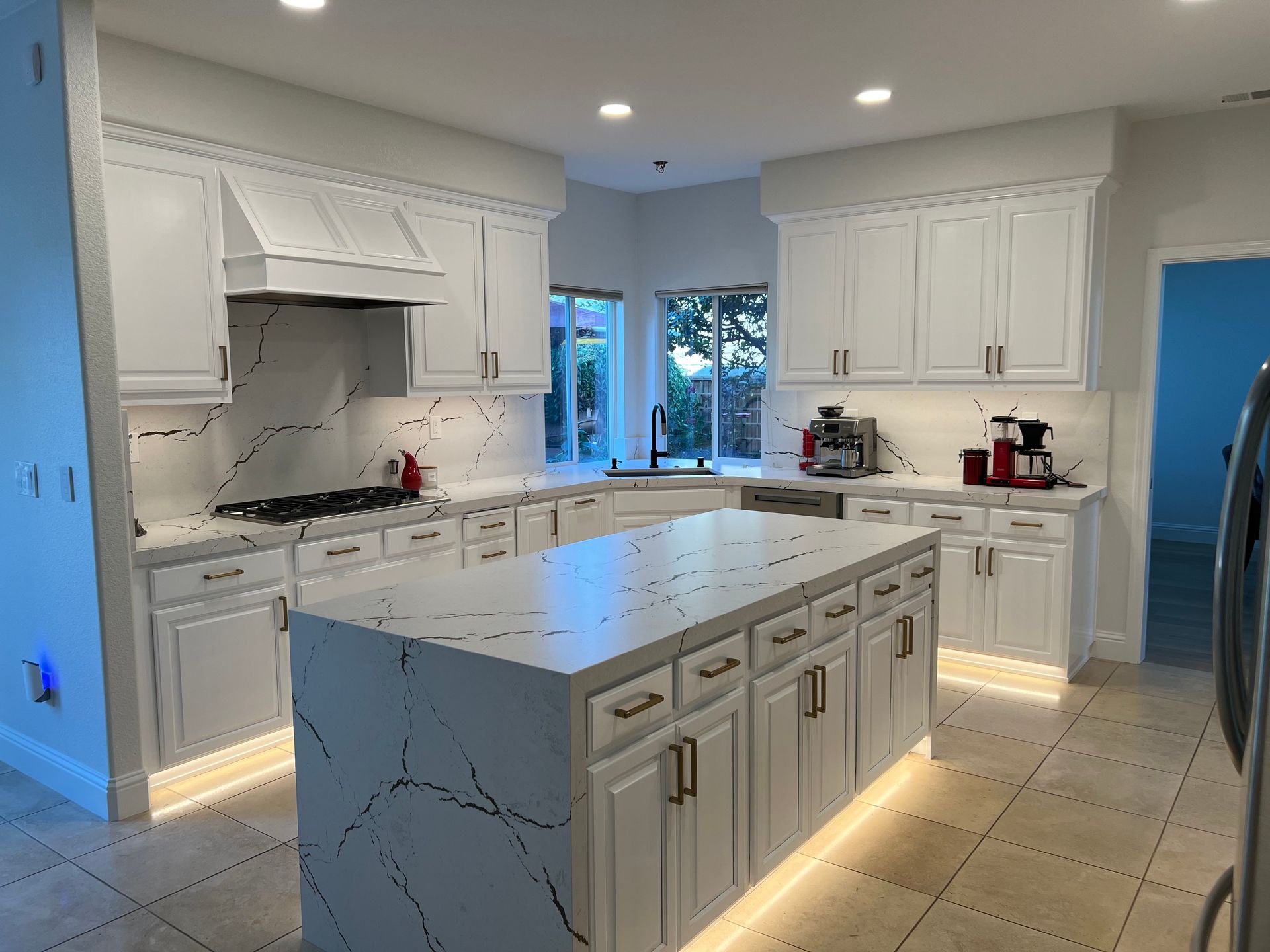 A kitchen with white cabinets and a large island in the middle.