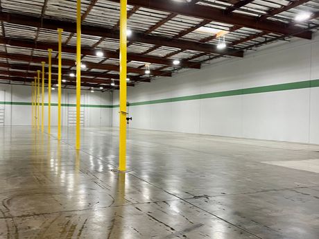 an empty warehouse with yellow poles and green stripes on the walls