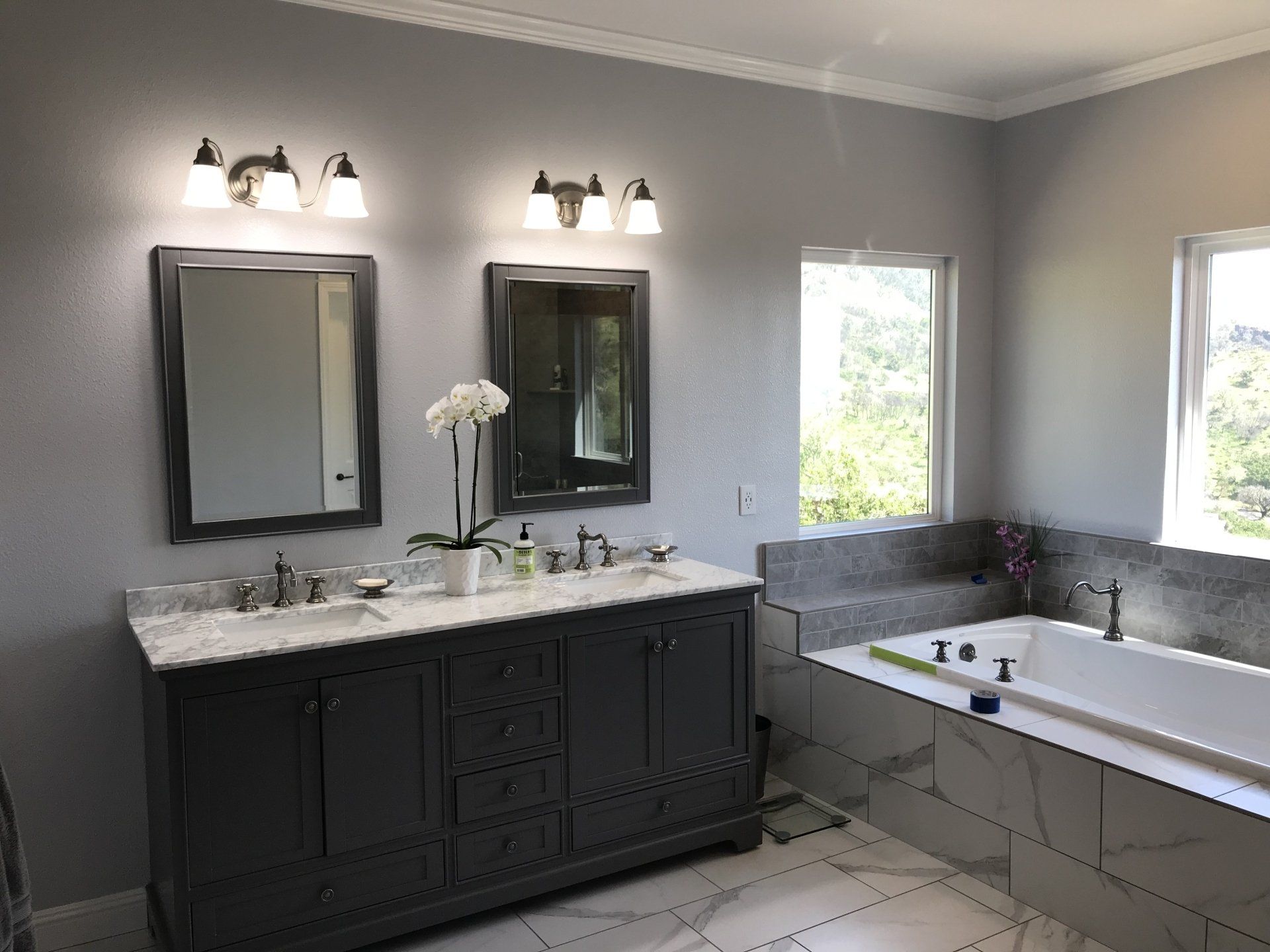 A bathroom with two sinks , two mirrors and a bathtub.