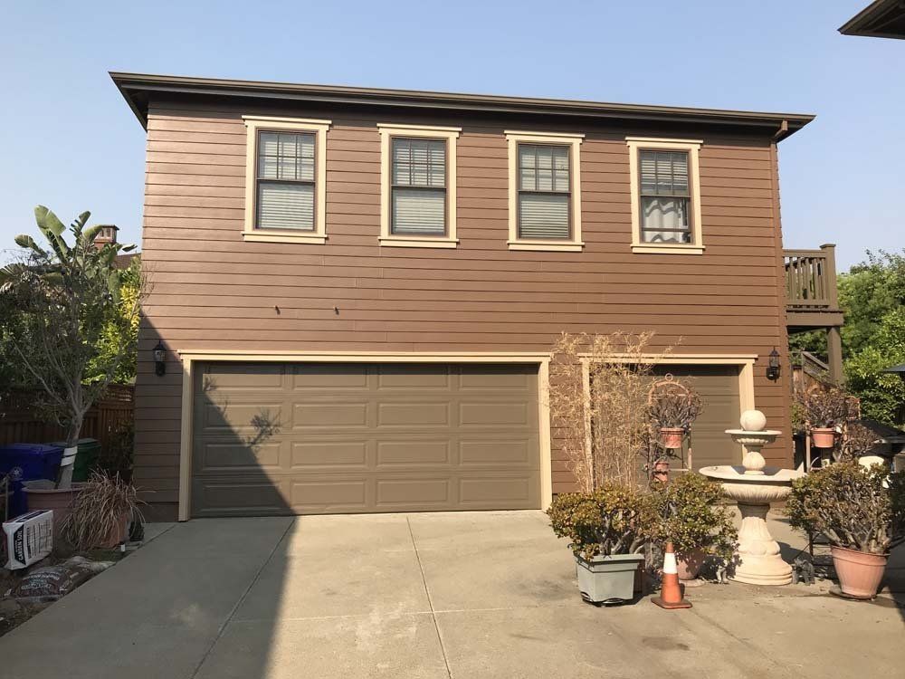 A brown house with a garage and a driveway