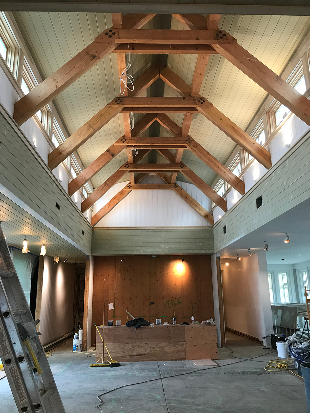 A large room with a wooden ceiling and a ladder.