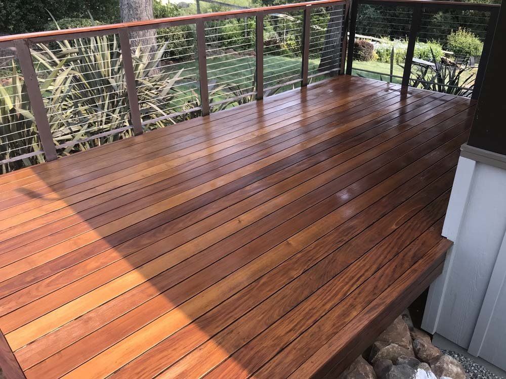 A wooden deck with a metal railing and a fence