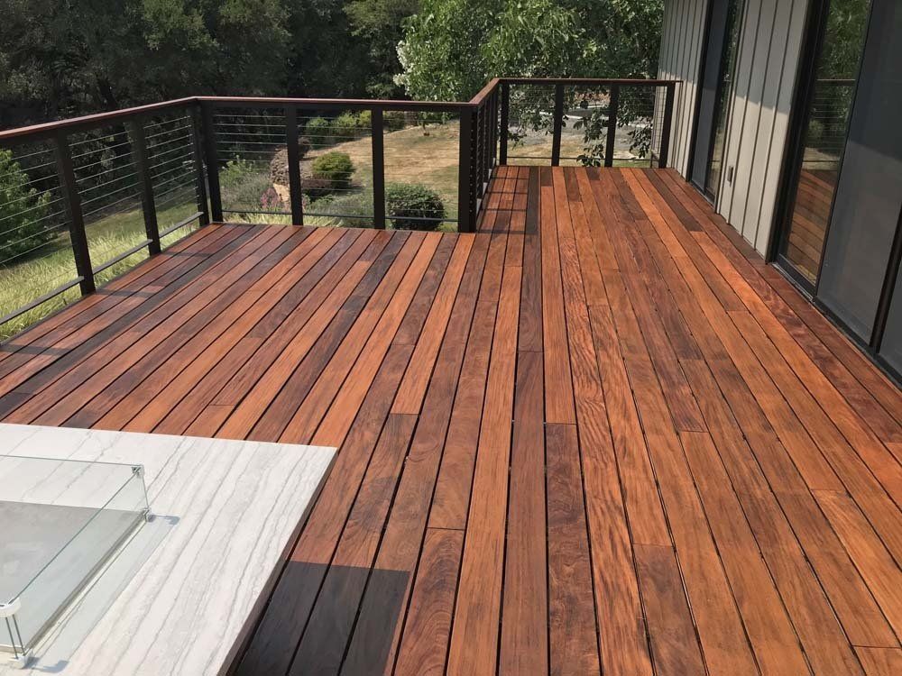 A wooden deck with a black railing and a white table