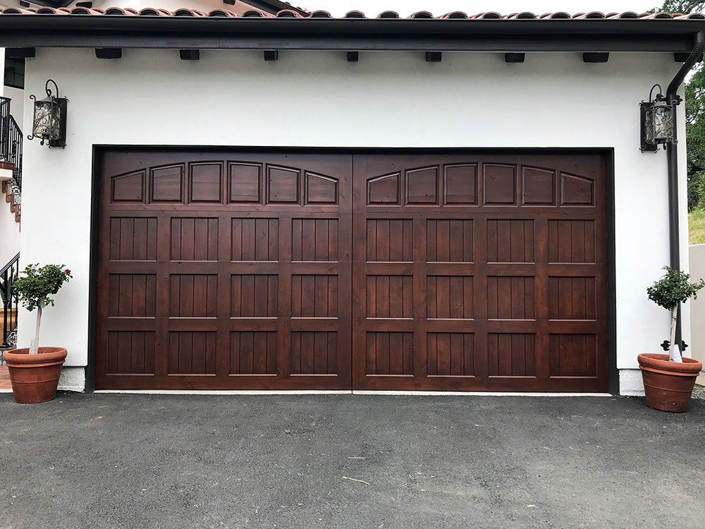 A large wooden garage door with potted plants in front of it
