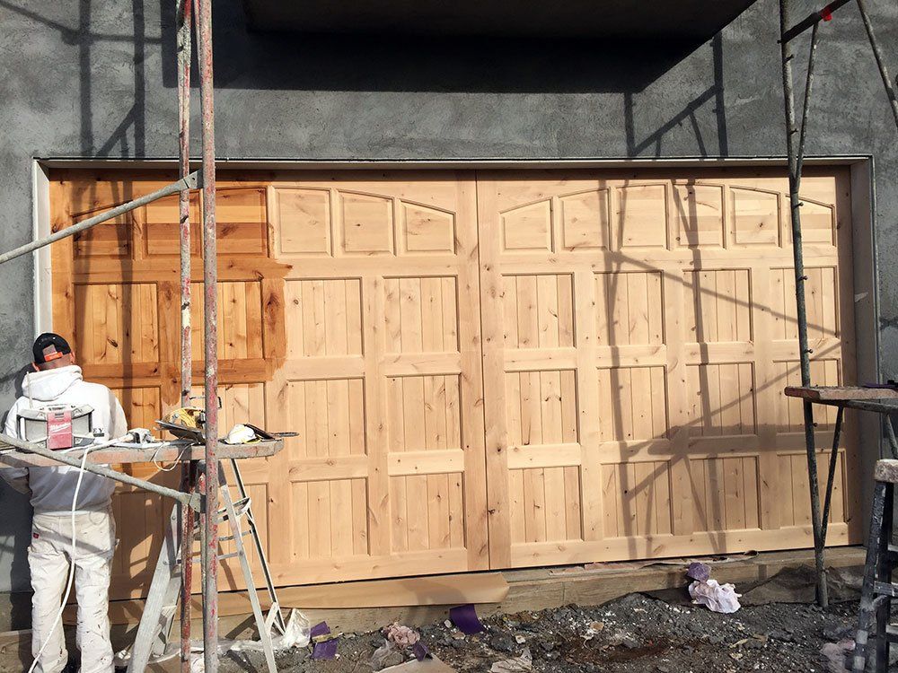 A man is standing in front of a wooden garage door.