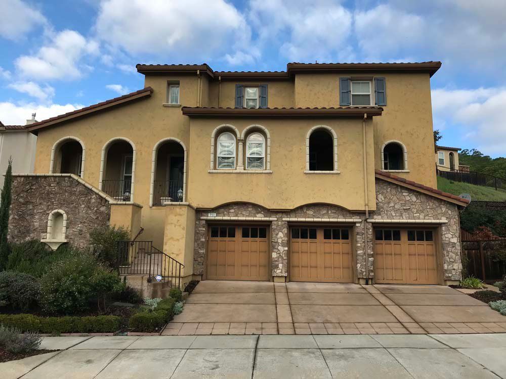 A large house with three garage doors and arched windows