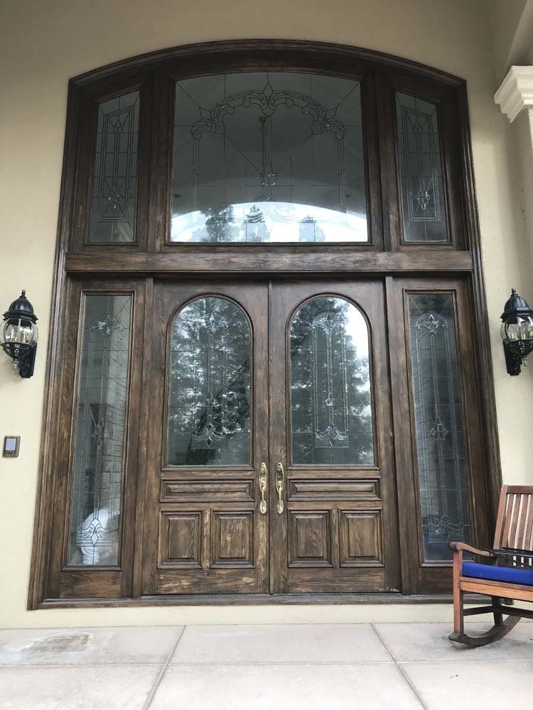 A rocking chair is sitting in front of a large wooden door.