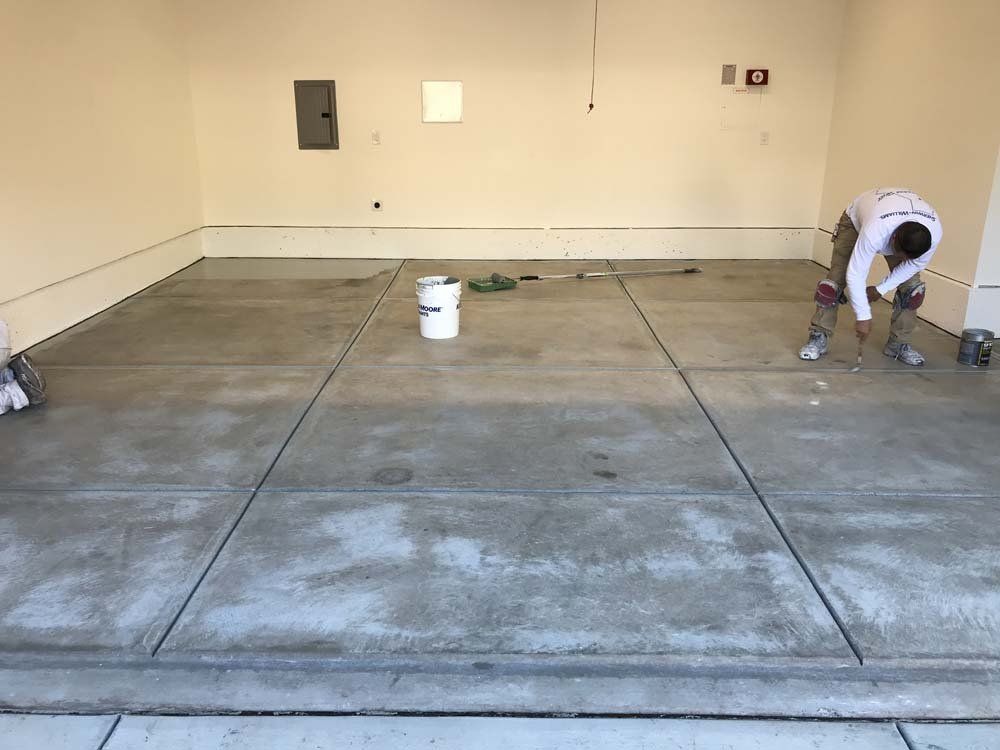 A man is working on a concrete floor in a garage.