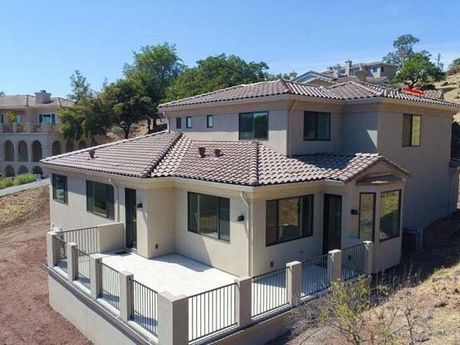 a large house with a tiled roof and a balcony is sitting on top of a hill .