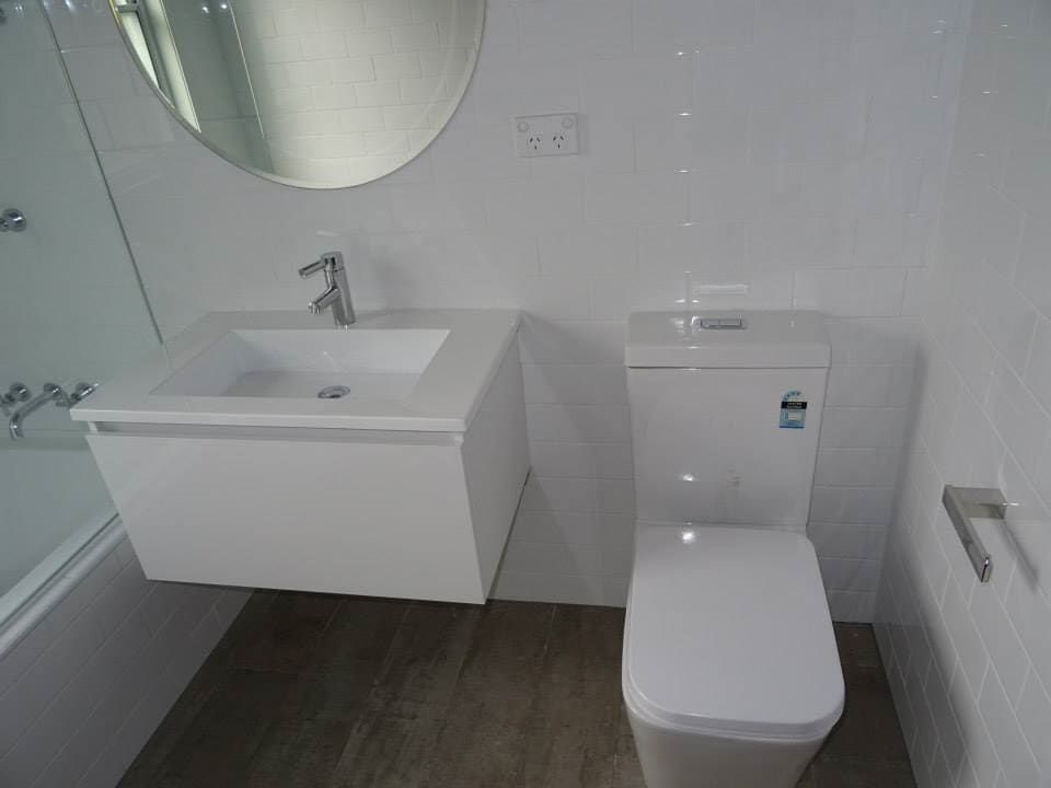 A Bathroom with a Toilet, Sink and Mirror — Illawarra Bathrooms in Wollongong, NSW	