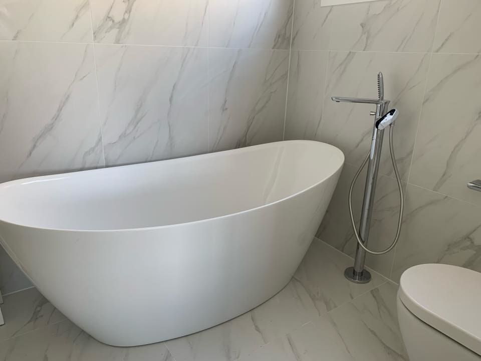 A White Bathtub is Sitting Next to a Toilet in a Bathroom — Illawarra Bathrooms in Wollongong, NSW	
