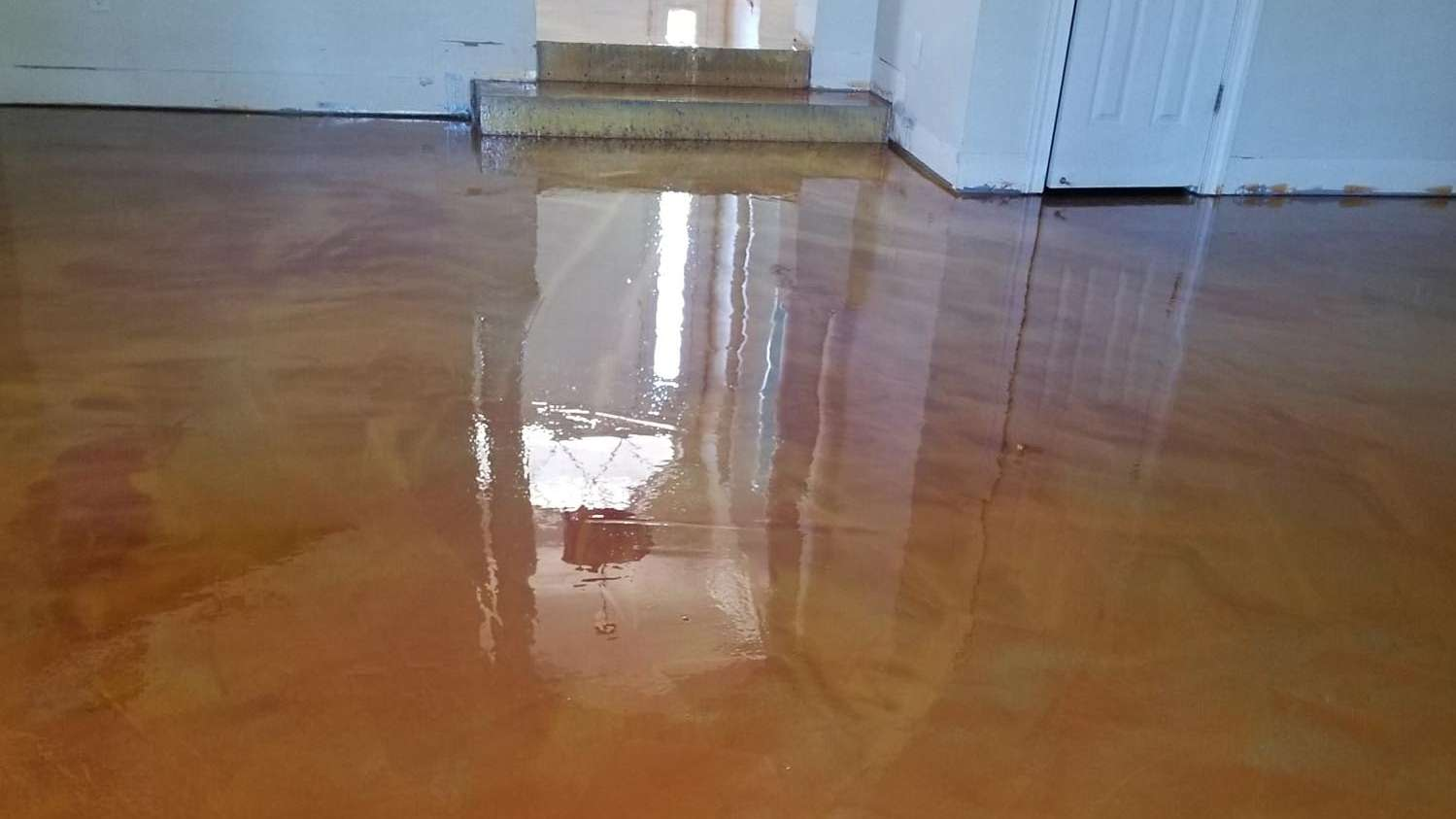 Glossy, metallic-orange epoxy floor reflecting the surrounding room and doorway.