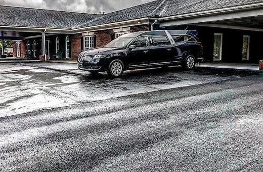Black SUV parked outside a brick building on a snow-covered driveway