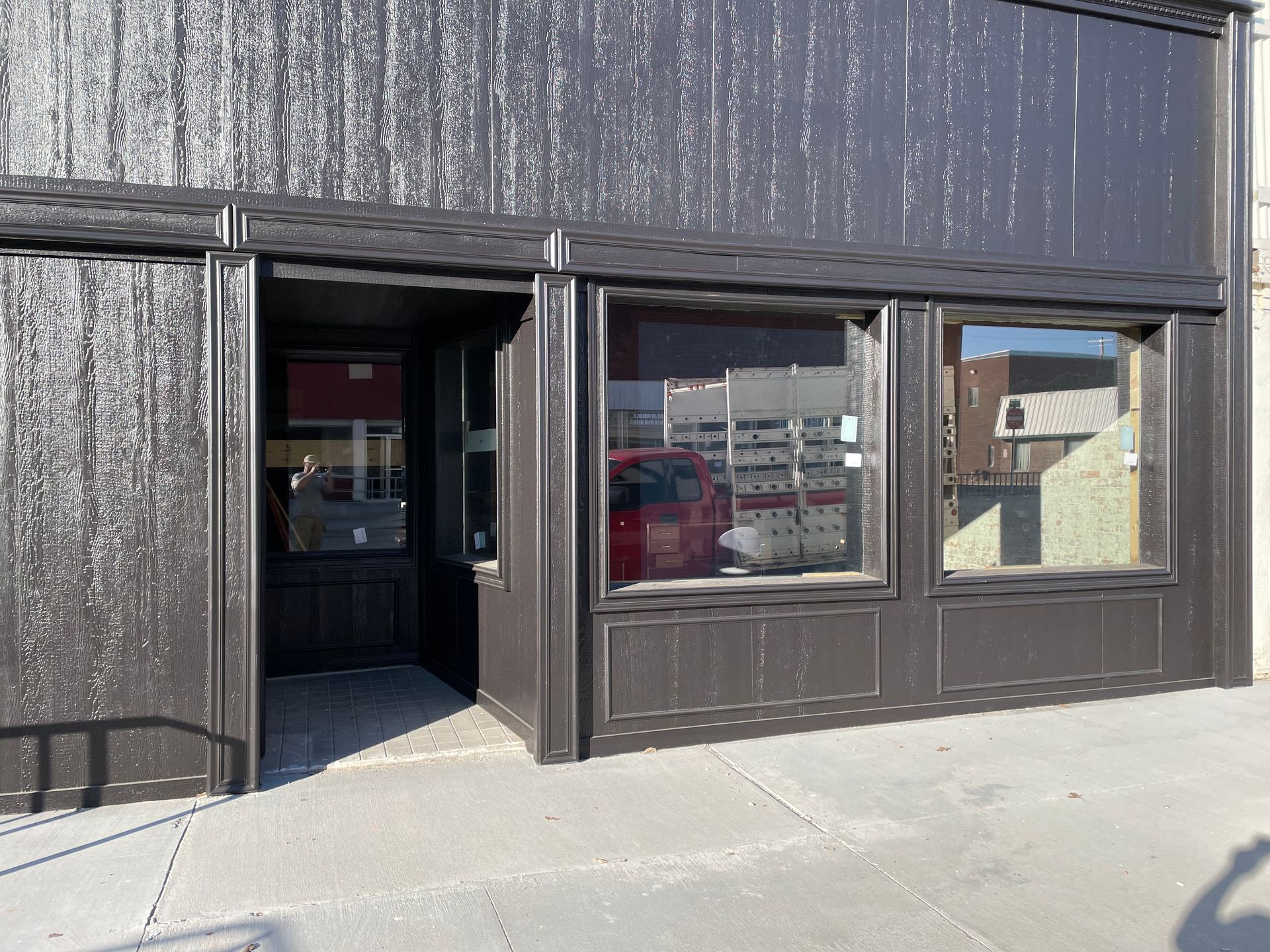 A black building with a red car parked in front of it.
