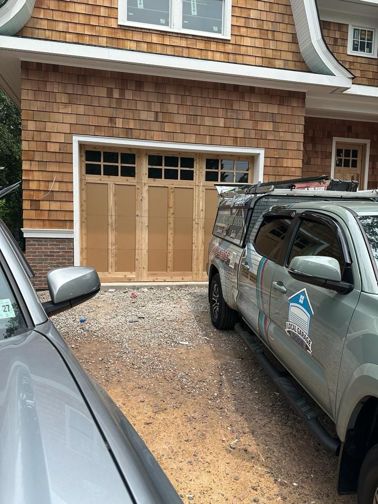 A truck is parked in front of a house with a wooden garage door.