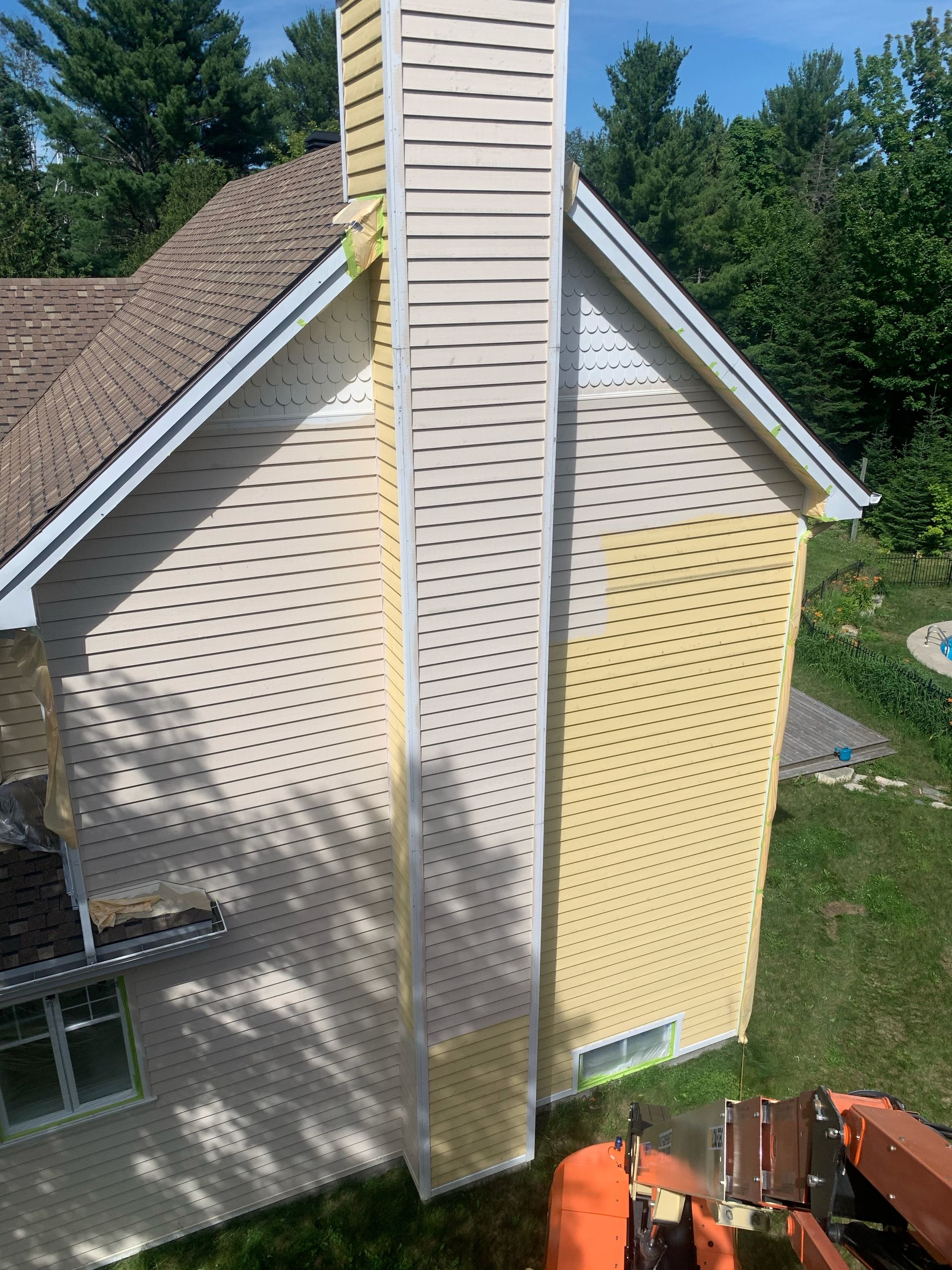 une maison jaune avec une cheminée blanche sur le côté.