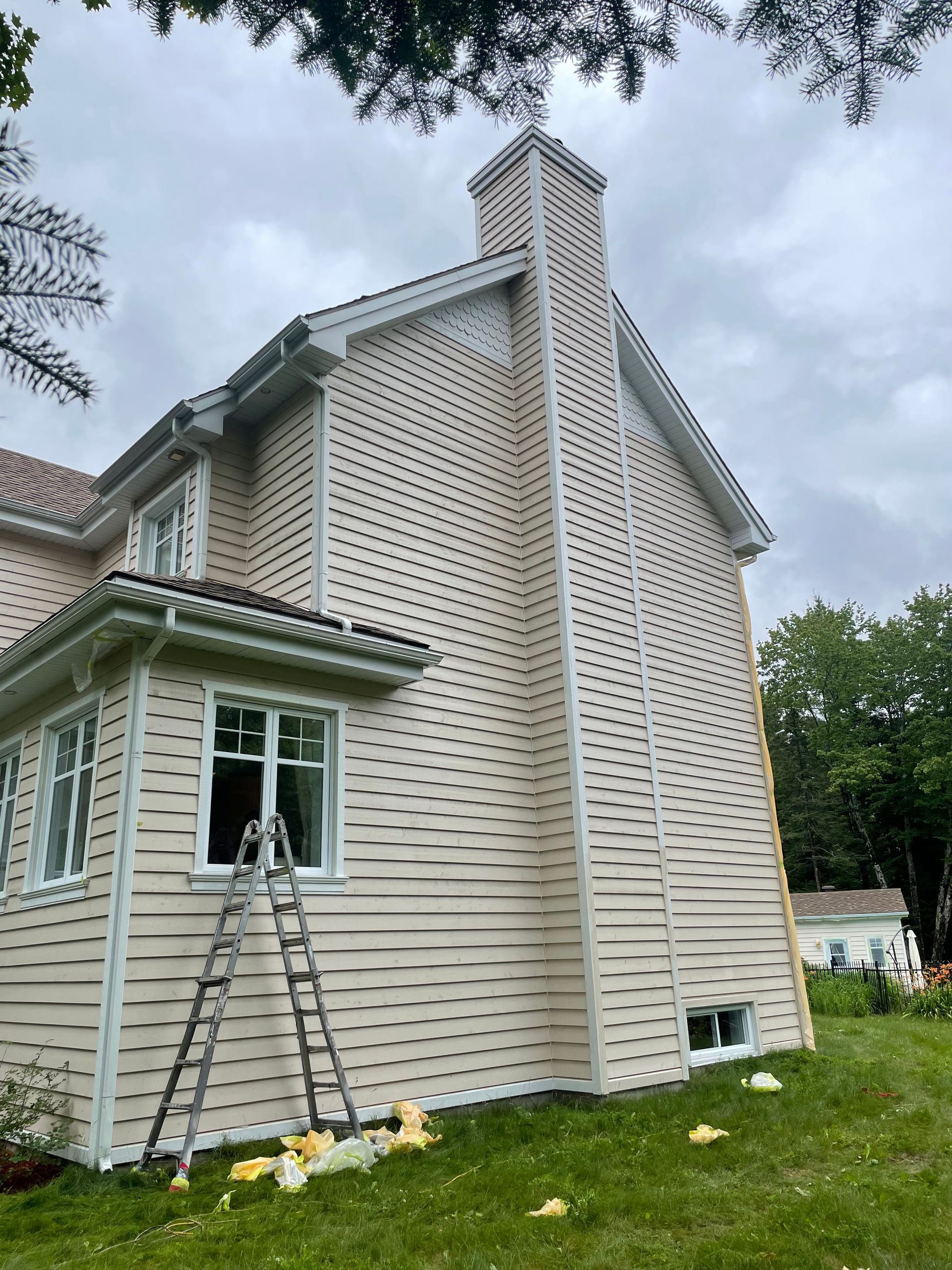 une maison avec une échelle sur le côté est en train d'être repeinte.