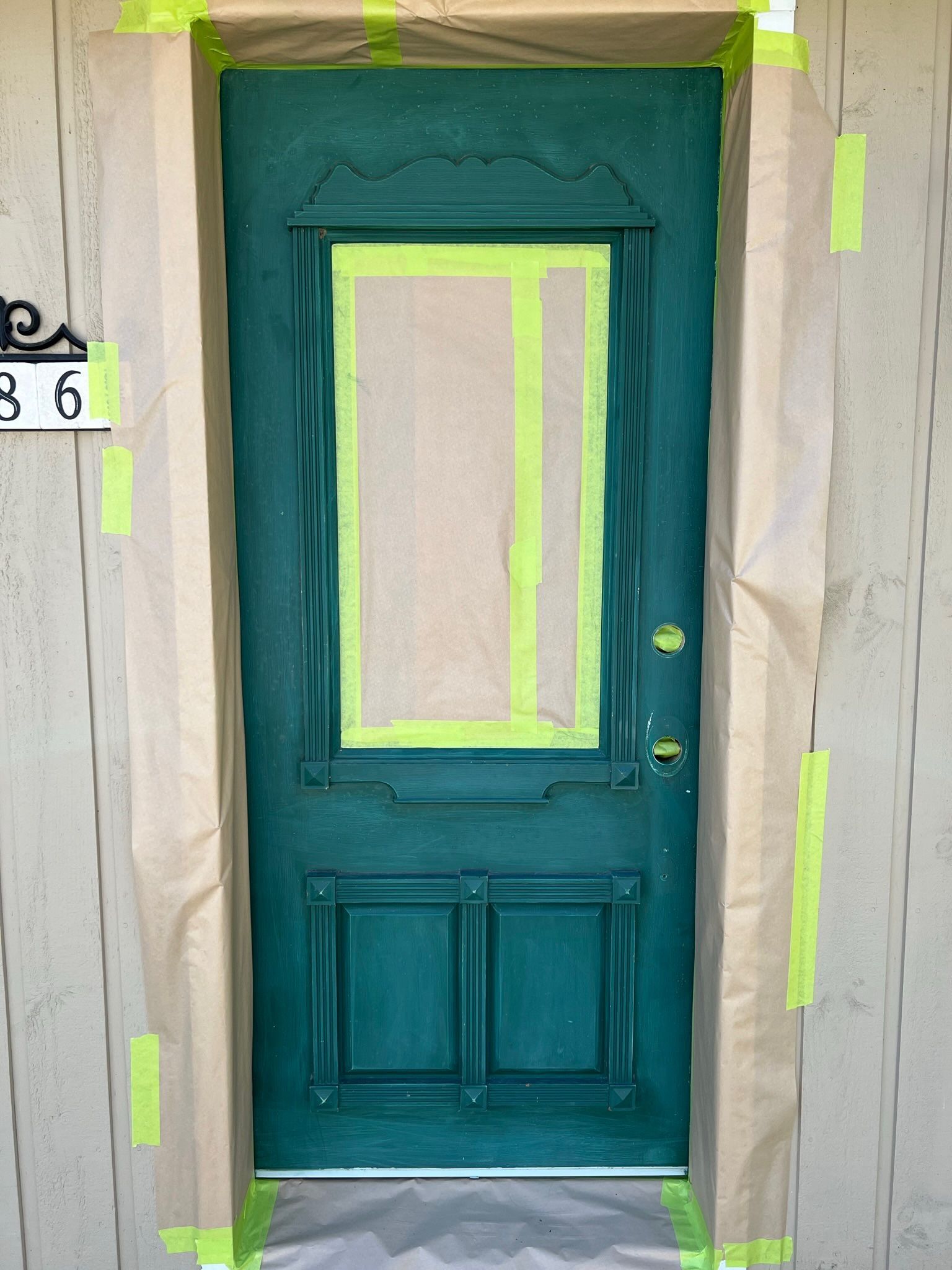 une porte verte est collée sur un mur avec du ruban adhésif jaune.