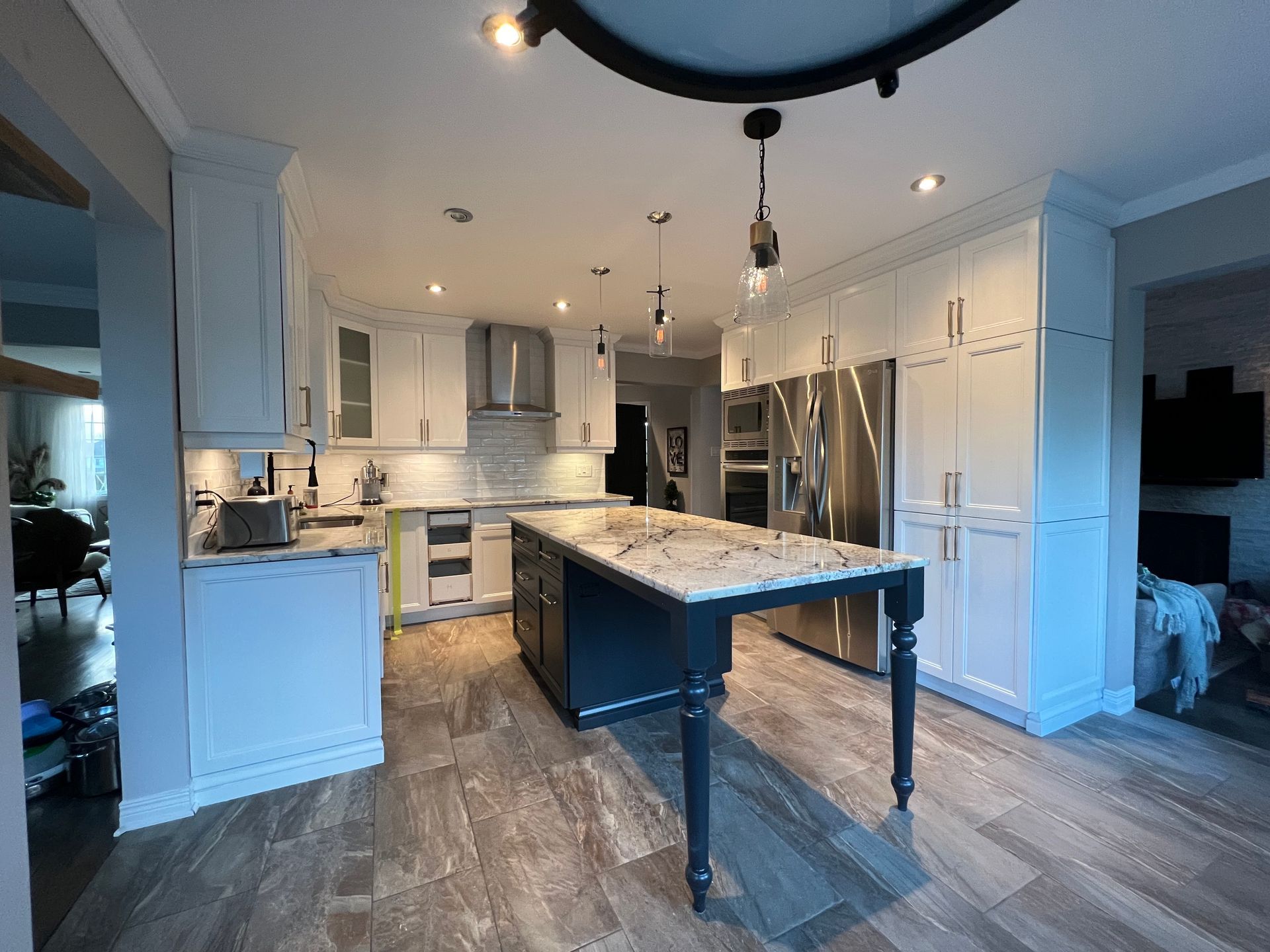 A kitchen with white cabinets and stainless steel appliances and a large island in the middle.