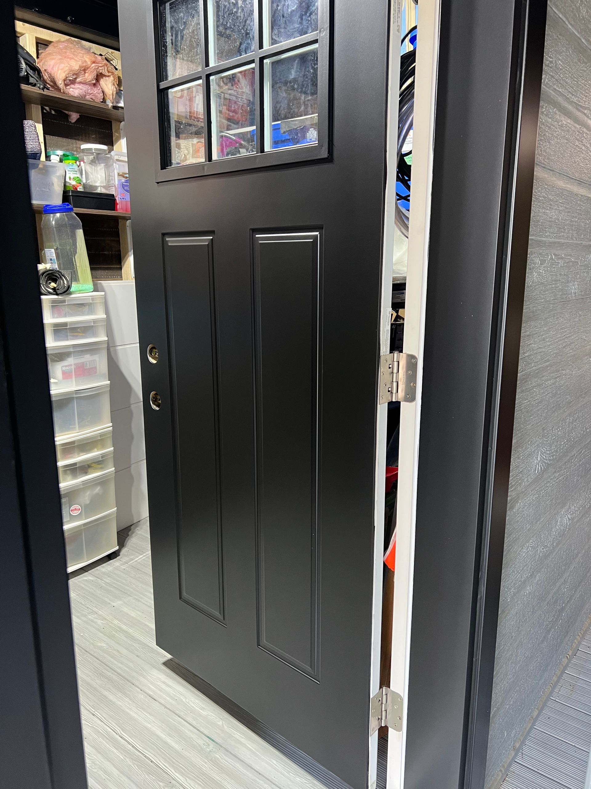 une porte noire avec une fenêtre en verre est ouverte dans une pièce.
