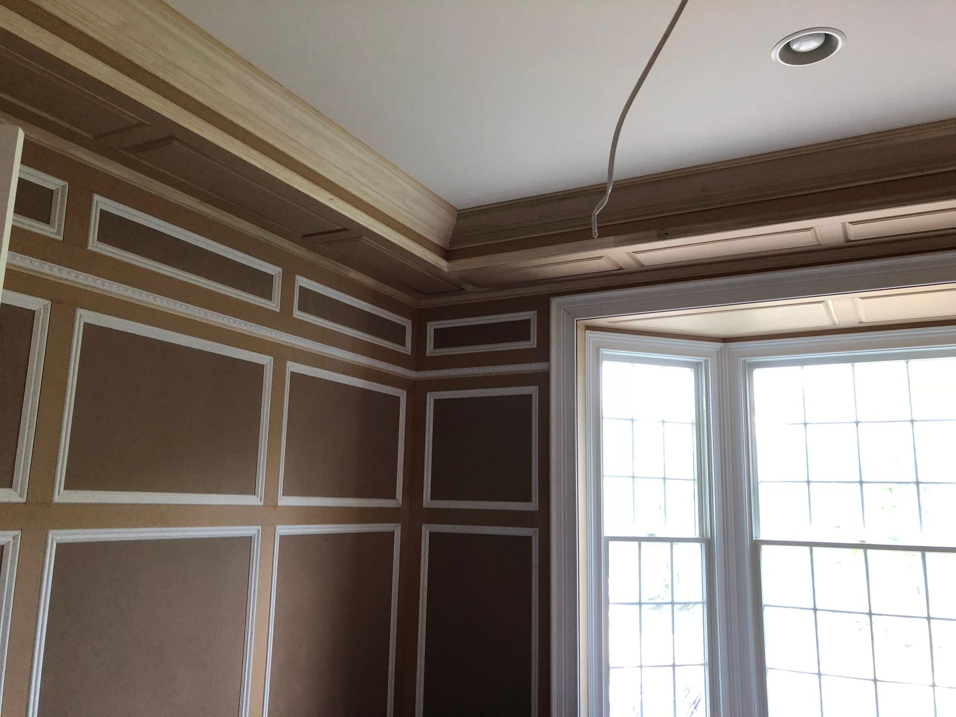 A room with brown walls and white trim and a window