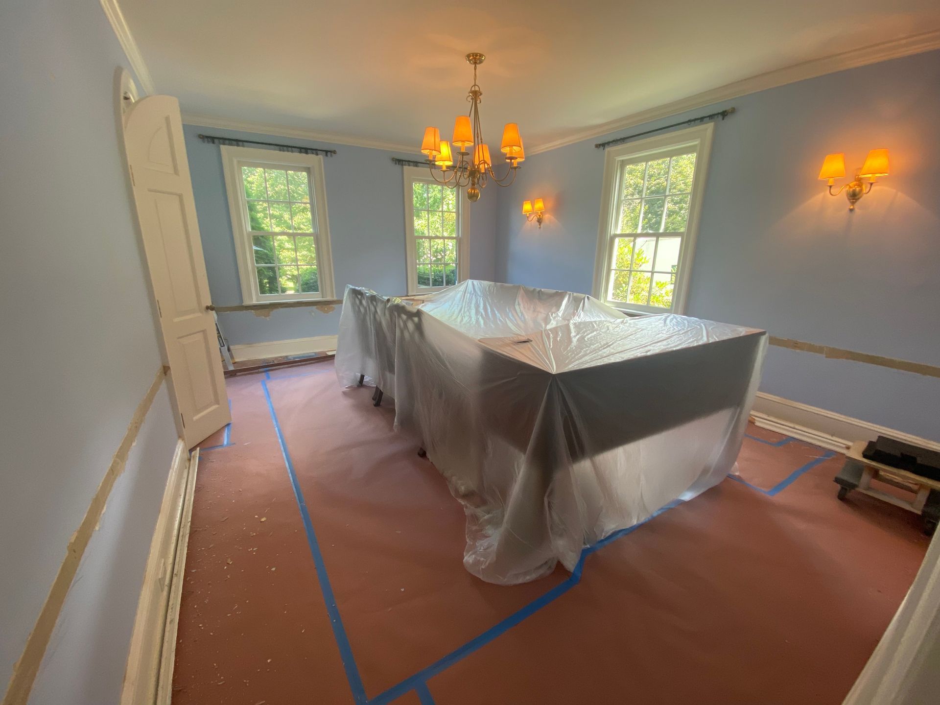 A room with a table and chairs covered in plastic.