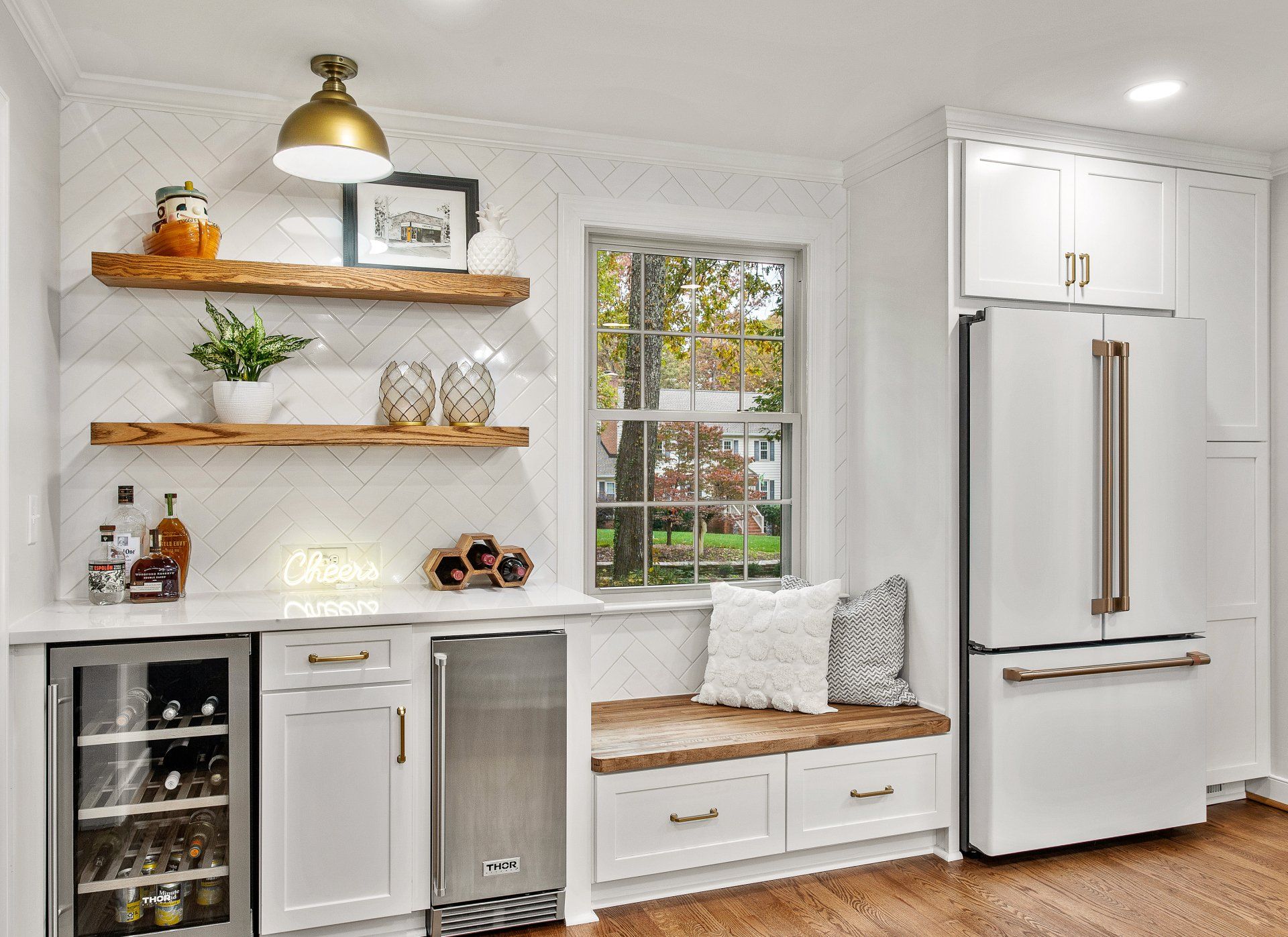 Kitchen Remodel: A kitchen with white cabinets , a stainless steel refrigerator , a wine cooler and a window seat.