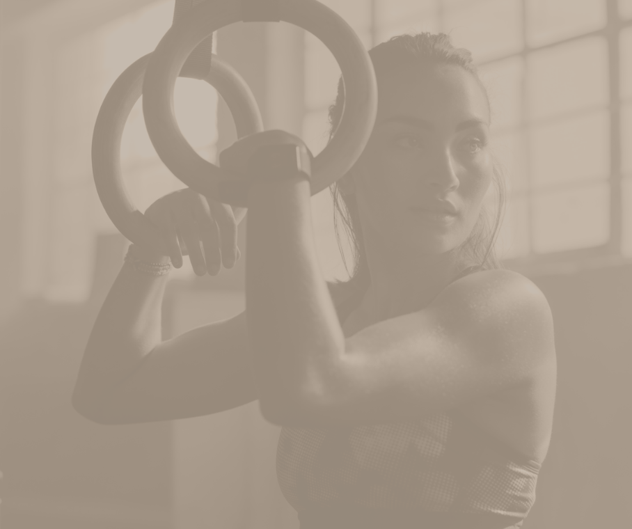 A woman is holding gymnastic rings over her head in a gym.