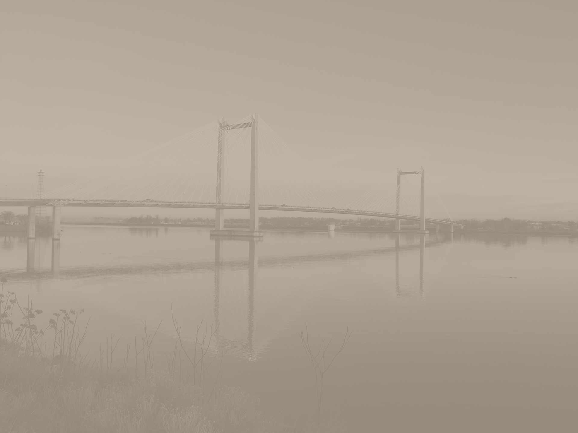 A bridge over a body of water in the fog.