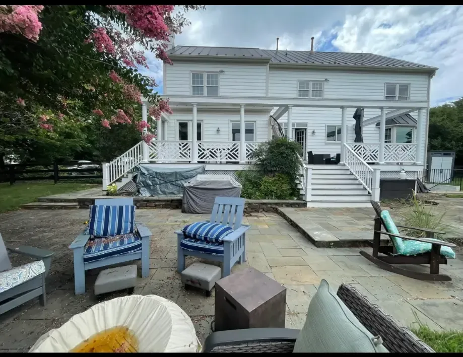 a large white house with a patio and chairs in front of it .