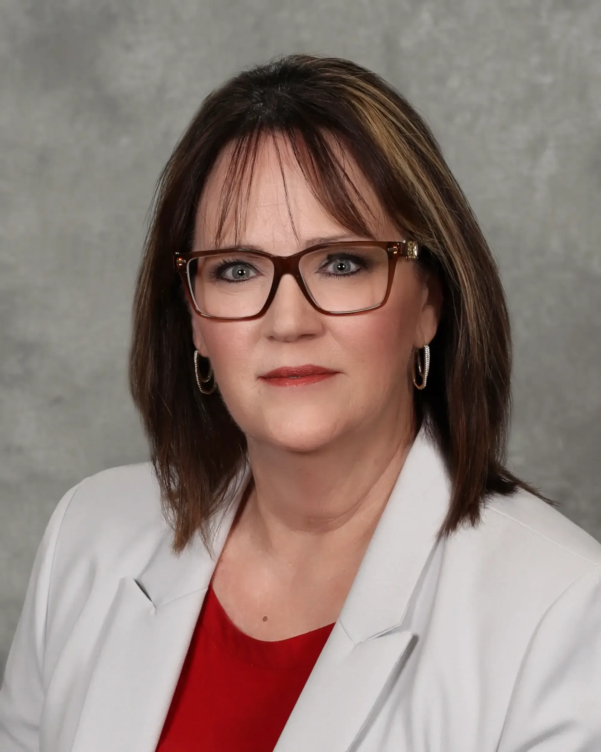 A woman wearing glasses and a white jacket