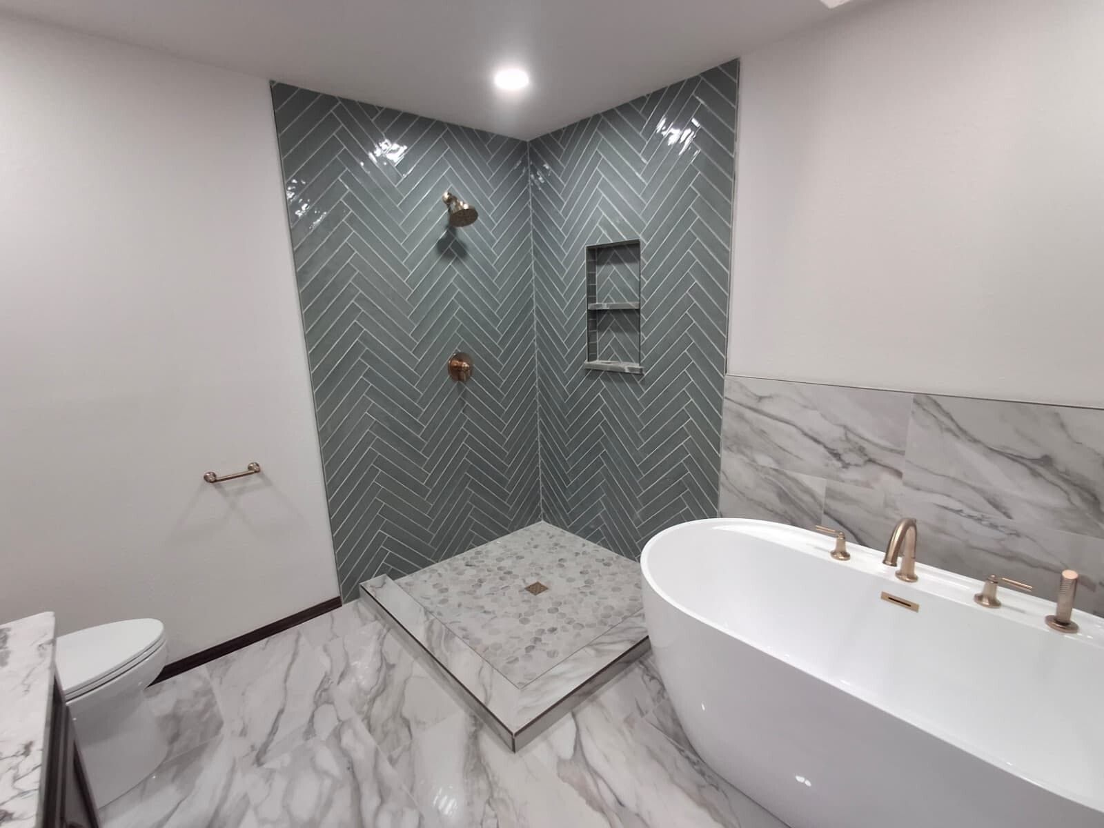Modern bathroom with glass shower, marble walls, and freestanding white tub