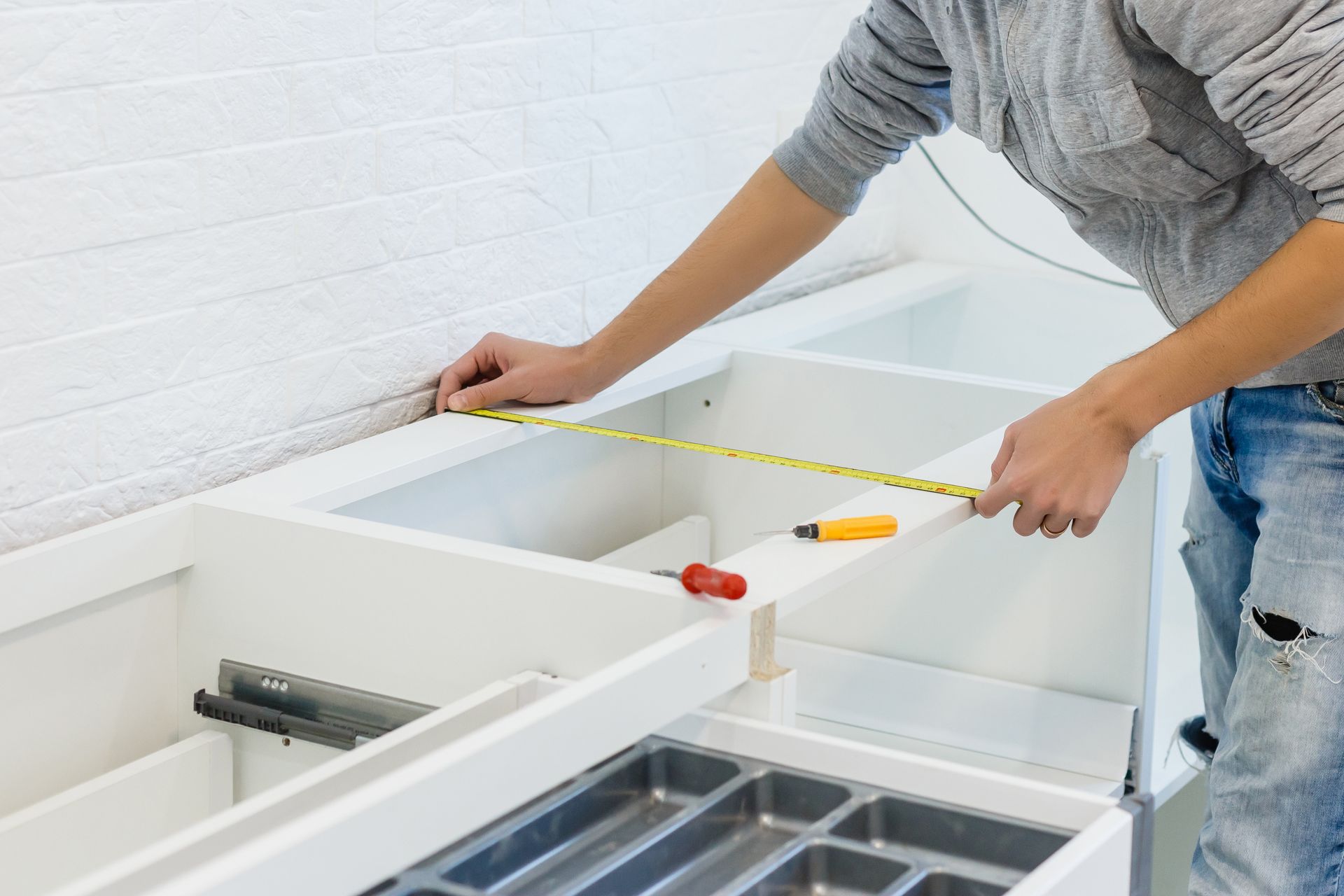 Remodeler measuring new white kitchen cabinets