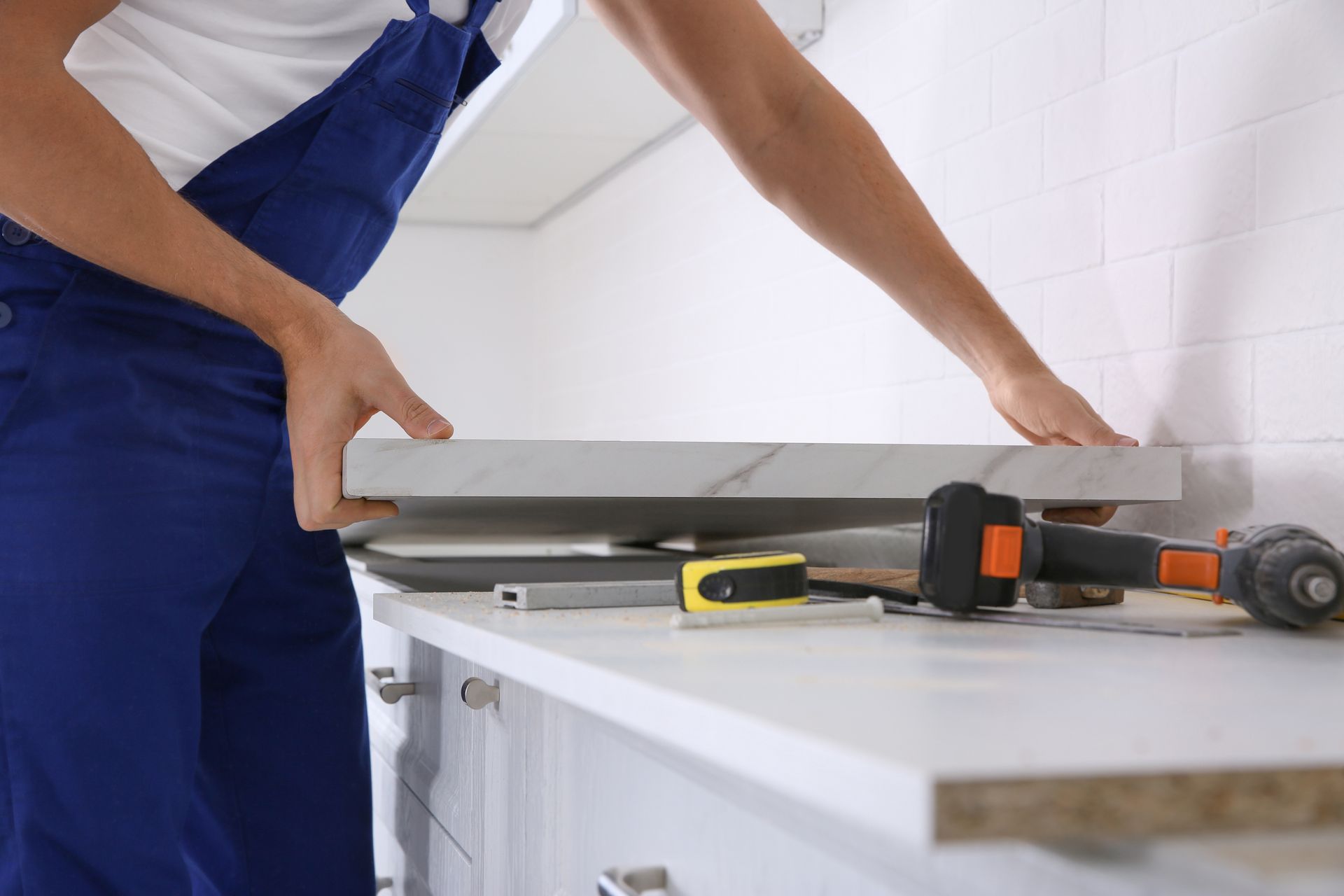 Worker installing new countertop in kitchen, closeup.