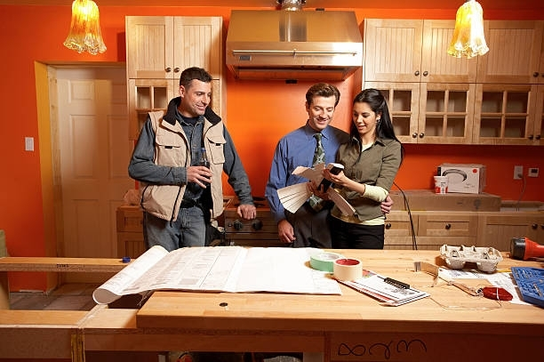 Home renovation planning in modern orange kitchen with blueprints, tools, and construction materials