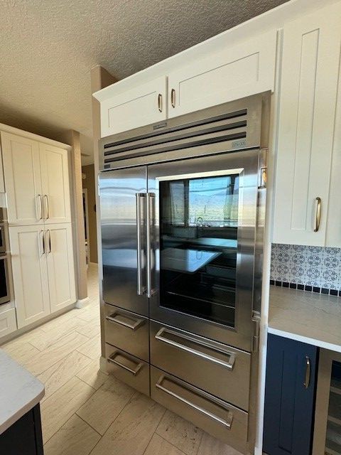 Built-in stainless steel refrigerator and double oven in a bright modern kitchen