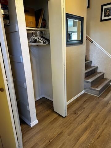 Open closet and staircase in a beige hallway with wood flooring