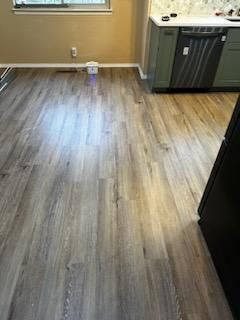 Kitchen floor with wood-look vinyl, beige walls, and cabinets along the right side.