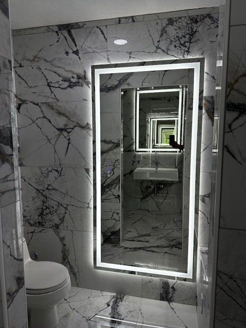 Modern marble bathroom with a lit mirror and an infinite mirror reflection effect.
