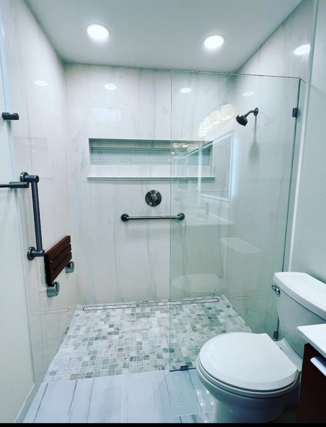 Small modern bathroom with walk-in shower, white tile walls, glass door, and toilet on the right