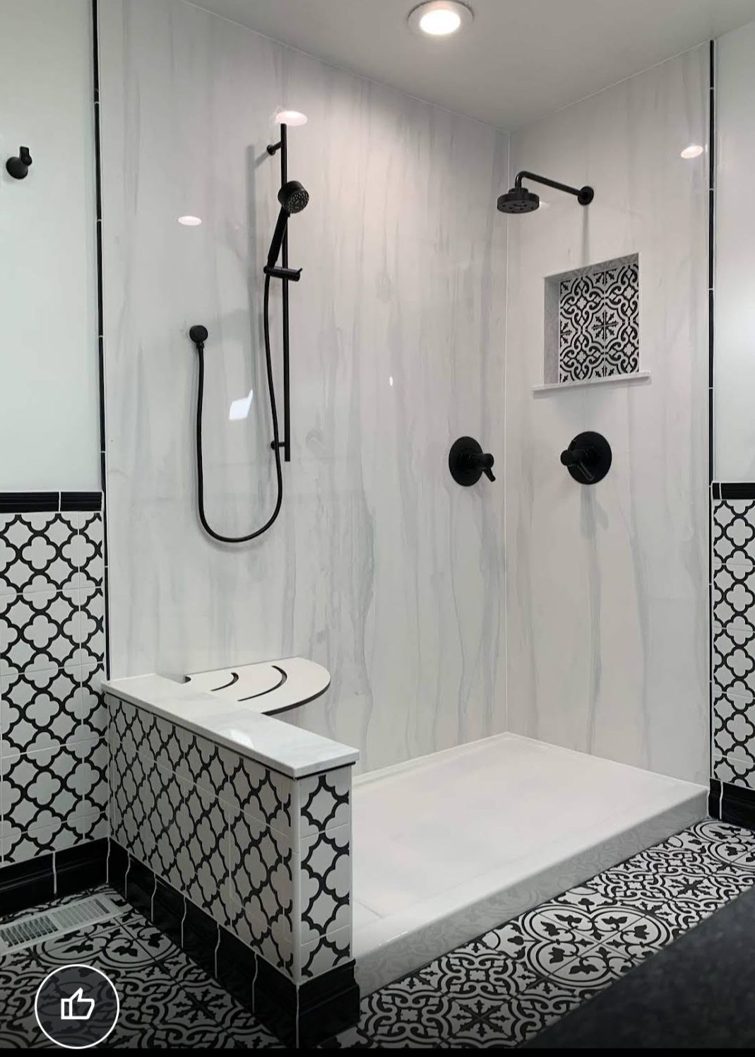 Modern white walk-in shower with black fixtures, tiled bench, and hexagonal floor accents